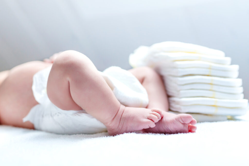 Baby next to pile of diapers