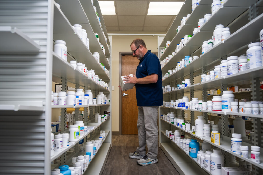 Pharmacist standing next to medications in pharmacy