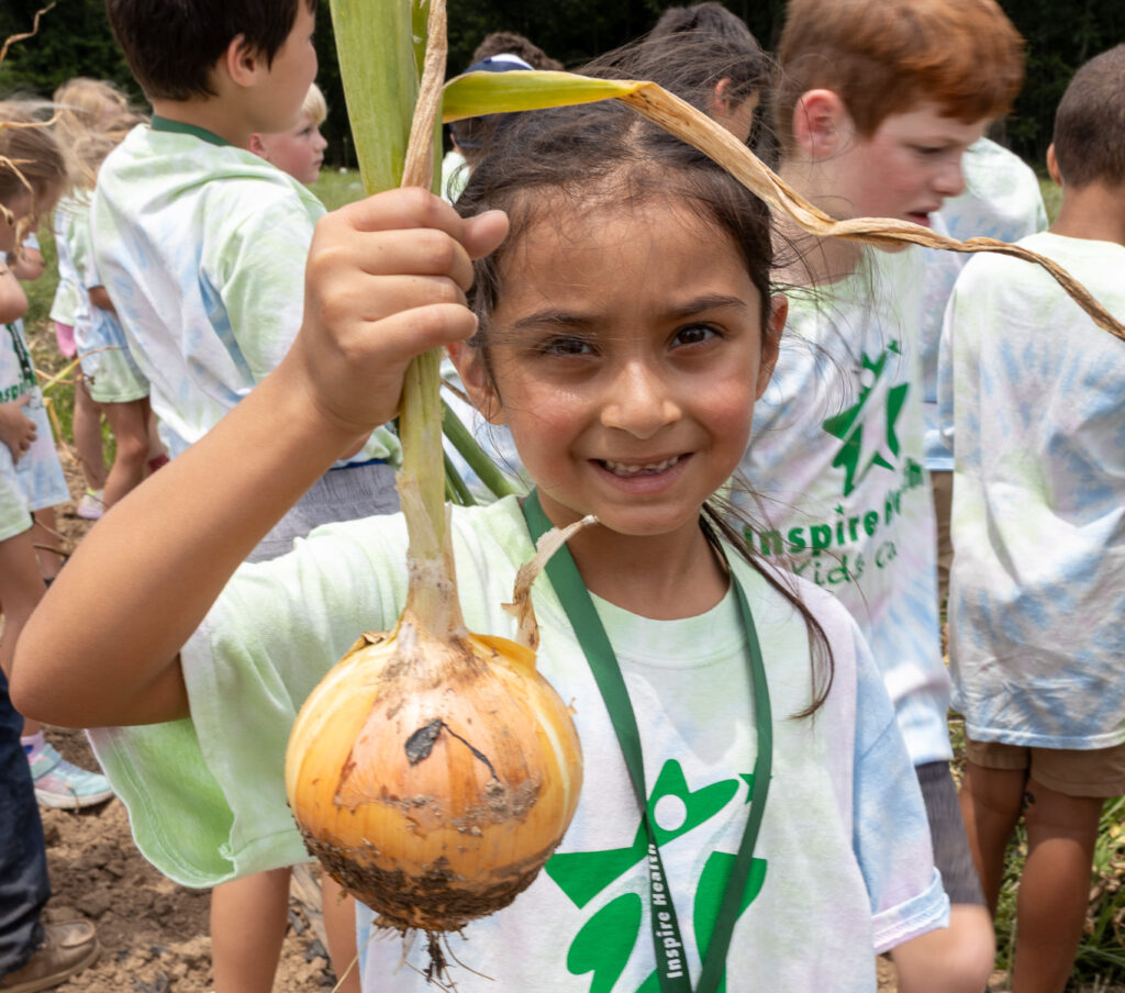 child posing with onion from farm