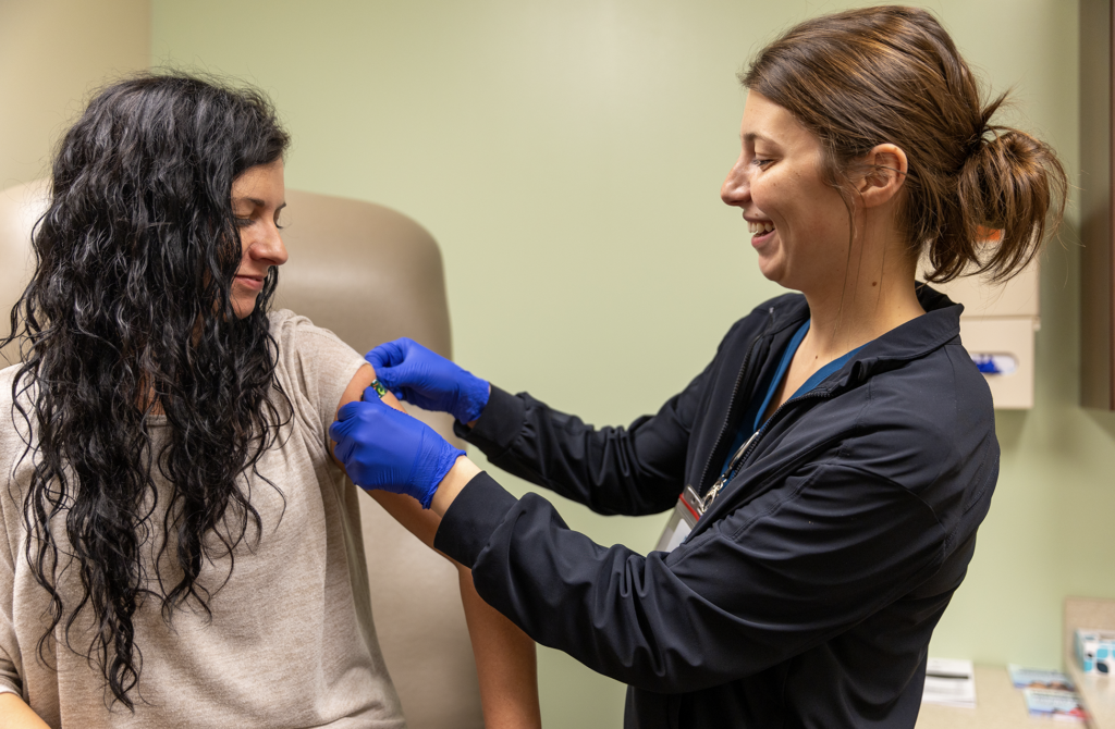 nurse placing bandage on patient's arm after flu shot
